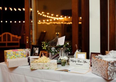 A table holding gifts, a bird cage with cards in it, a guest book, and some photographs in frames.