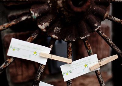 Close-up of the spokes of a wagon wheel with place cards clipped to the spokes with clothespins.