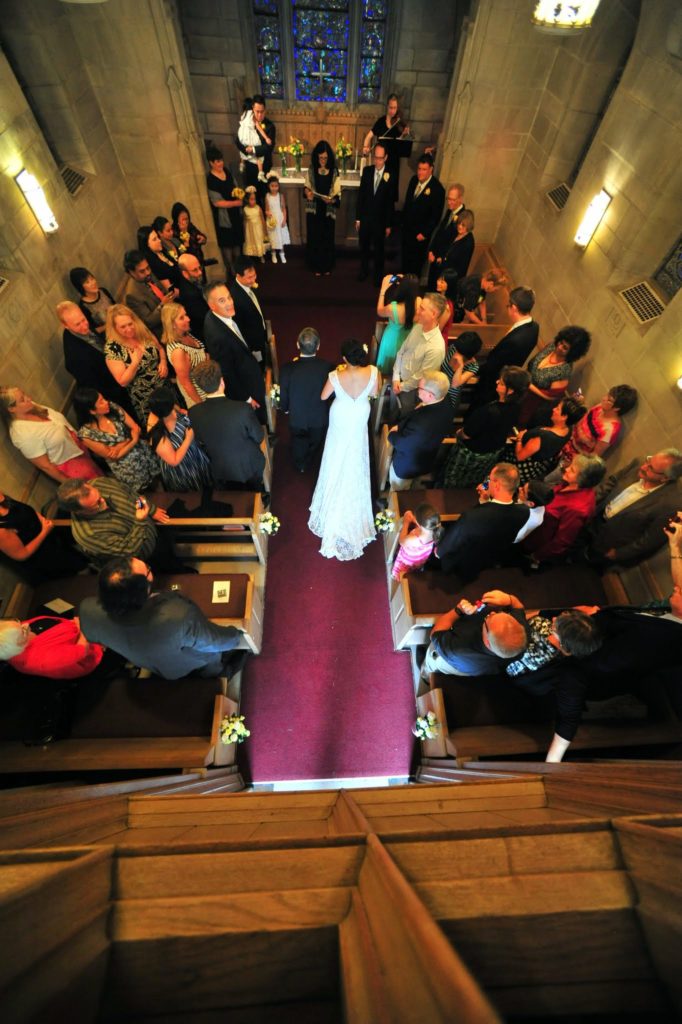 A small wedding chapel with a bride walkingn down the aisle, as seen from above.