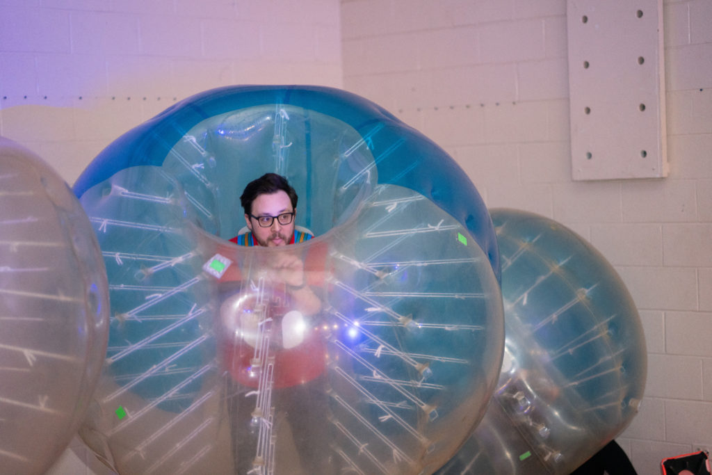 An adult in a large, inflatable ball, looking mischievous.
