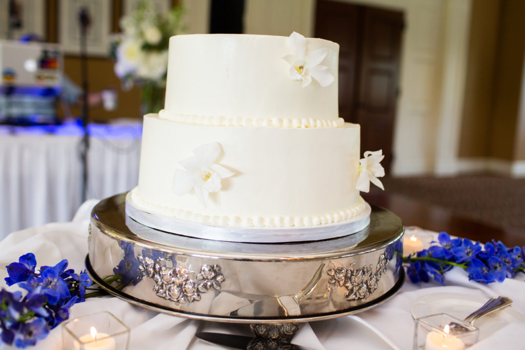A 2-tier white wedding cake with white and blue flower decorations