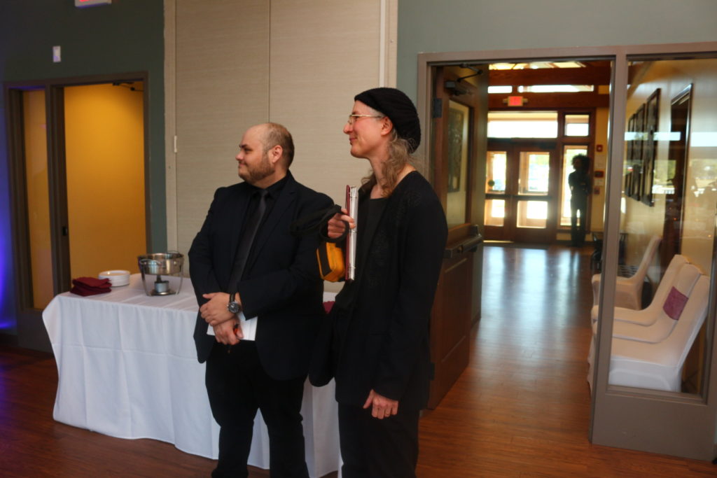 Two people wearing black standing near a buffet table.